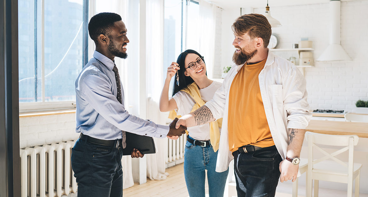 African,American,Real,Estate,Broker,And,Smiling,Couple,Sealing,Deal A leasing staff agent shakes hands with a new renter.